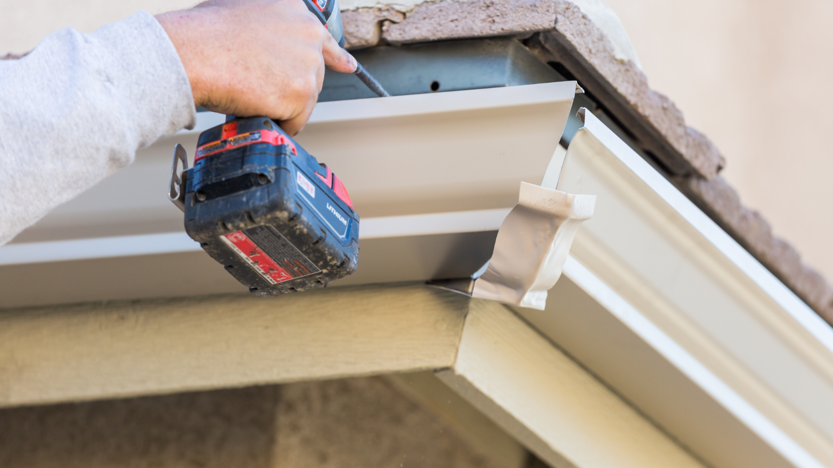 A man using a drill to fix a gutter gutter