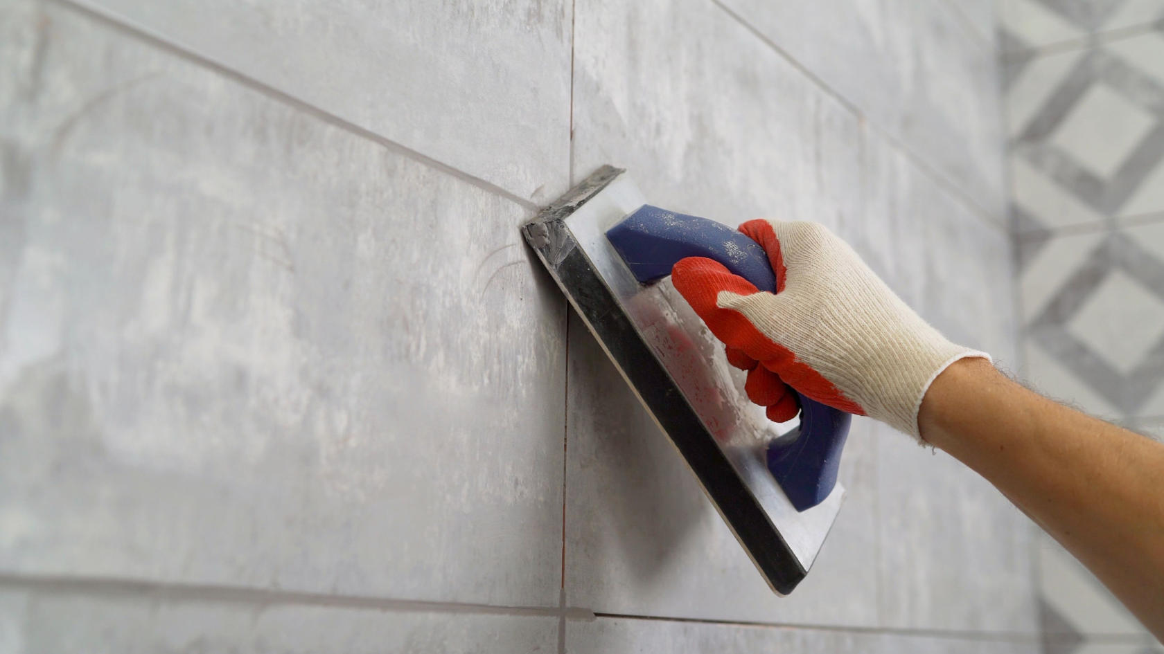 A person using a sponge to clean a tile wall